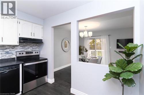 Kitchen with white cabinetry, mosaic tile backsplash, stainless steel range, and black dishwasher - 543 Drummerhill Crescent, Waterloo, ON 