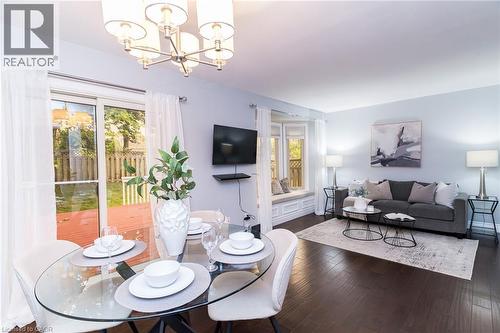 Hardwood flooring throughout, recessed bay window with seating, sliding glass doors to outdoor decking, and a contemporary chandelier - 543 Drummerhill Crescent, Waterloo, ON 