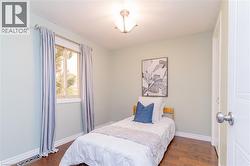 Wood-finish flooring, single window, overhead light fixture, light wall color, white trim - 