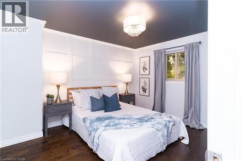 Wood-finish flooring, accent wall with panel molding, single window with roller shade, and a flush-mount crystal chandelier - 543 Drummerhill Crescent, Waterloo, ON 