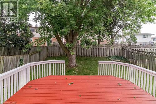 Expansive backyard featuring a red wood-finish deck with white railings, a mature shade tree, and a lush green lawn - 543 Drummerhill Crescent, Waterloo, ON 