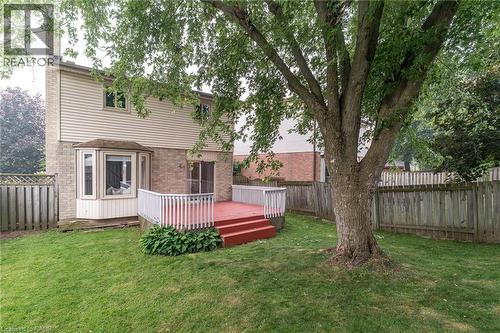 Expansive backyard featuring a mature tree, privacy fencing, and a multi-level deck with white railings - 543 Drummerhill Crescent, Waterloo, ON 