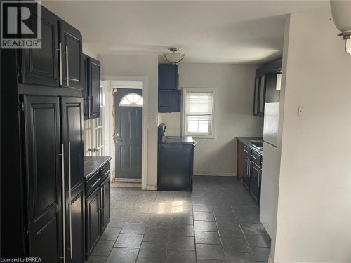 Kitchen featuring dark cabinetry with silver-tone hardware, a window with blinds, and tile flooring - 258 Wellington Road, London, ON 