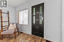 Entryway featuring a black panel door with decorative glass inserts, wood-finish flooring, and a large window with white trim - 