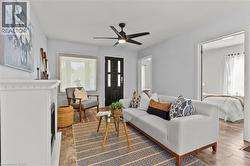 Wood-finish flooring throughout, white fireplace with mantle, and a modern black ceiling fan - 