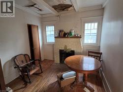 Interior room featuring a cream-colored painted brick fireplace, multi-pane windows with detailed millwork, and hardwood flooring - 