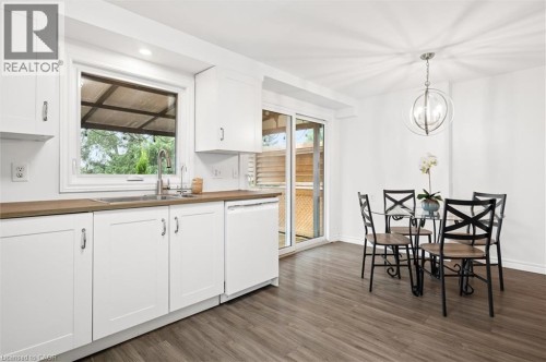 White shaker cabinetry with wood-finish countertops, stainless steel sink with gooseneck faucet, and white dishwasher - 76 Cluthe Crescent, Kitchener, ON 
