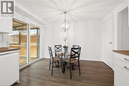 Wood-finish flooring, sliding glass door, white cabinetry, wood countertops, and a modern light fixture - 76 Cluthe Crescent, Kitchener, ON 