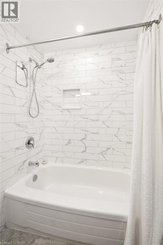 Subway tile shower surround with integrated niche, chrome fixtures, and a curved bathtub - 76 Cluthe Crescent, Kitchener, ON 