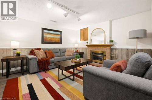 Brick-clad fireplace with a brass-toned insert, wood mantel, and track lighting - 76 Cluthe Crescent, Kitchener, ON 