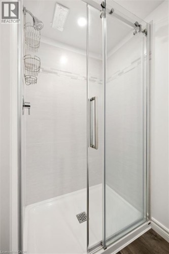 Glass-enclosed shower with a sliding door, chrome fixtures, tiled walls, and a recessed light - 76 Cluthe Crescent, Kitchener, ON 