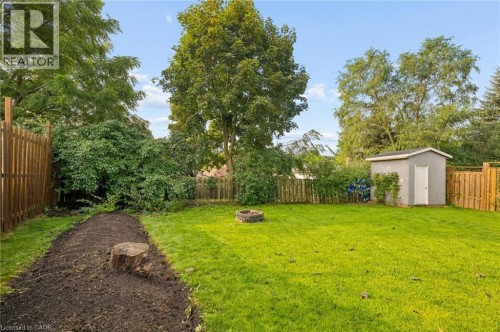 Expansive backyard with a manicured lawn, established trees, and a functional storage shed - 76 Cluthe Crescent, Kitchener, ON 