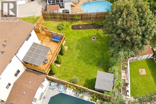 Expansive backyard featuring a manicured lawn, a multi-level wood deck with a covered section, a fire pit area, and a detached storage shed - 76 Cluthe Crescent, Kitchener, ON 