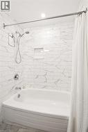 Subway tile shower surround with integrated niche, chrome fixtures, and a curved bathtub - 