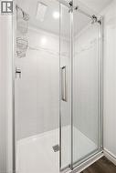 Glass-enclosed shower with a sliding door, chrome fixtures, tiled walls, and a recessed light - 