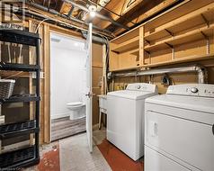 Laundry area with a washer and dryer, adjacent to a room with a toilet and wood-finish flooring - 