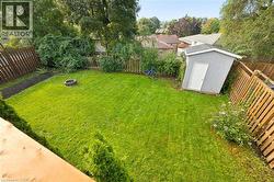 Expansive green lawn with a fire pit, bordered by natural-tone fencing and mature trees - 