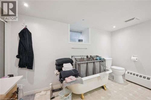 White walls with recessed lighting, a window with blinds, a toilet, and a clawfoot tub - 143 David Street, Kitchener, ON 
