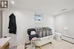 White walls with recessed lighting, a window with blinds, a toilet, and a clawfoot tub - 