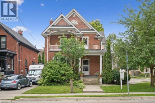 Brick exterior with detailed white trim, a covered front porch, and a second-story balcony with white railings - 143 David Street, Kitchener, ON 