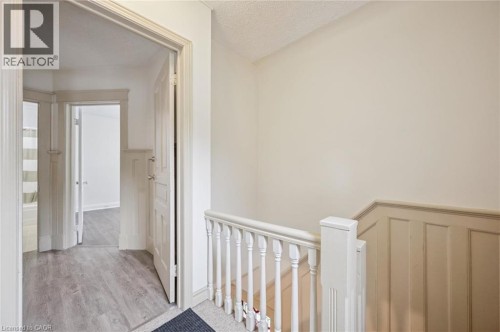 Panel molding accenting the stairwell, coordinating balustrade, wood-finish flooring, and white trim - 143 David Street, Kitchener, ON 