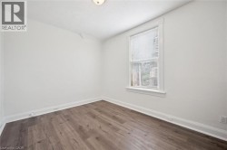 Light-filled room featuring wood-finish flooring, white walls, and a single window with blinds - 
