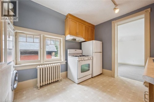 Kitchen featuring wood cabinetry, white appliances, patterned flooring, and a window - 143 David Street, Kitchener, ON 