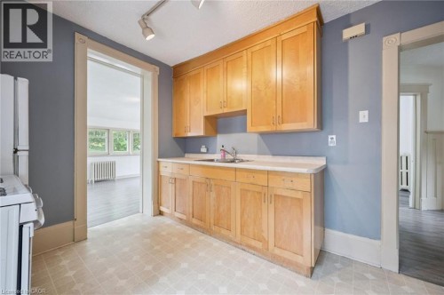 Kitchen featuring light wood cabinetry, a built-in sink, track lighting, and patterned flooring - 143 David Street, Kitchener, ON 
