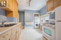Kitchen featuring light wood cabinetry, dual basin stainless steel sink, white range oven, and a stacked washer and dryer - 