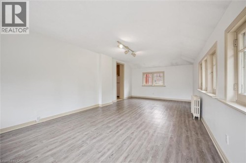 Spacious room with wood-finish flooring, track lighting, and multiple windows - 143 David Street, Kitchener, ON 