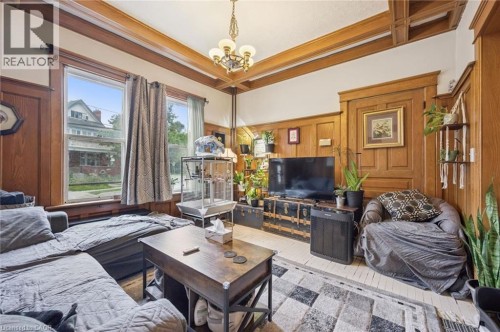 Wood-paneled walls and trim throughout, coffered ceiling with a central chandelier, and multiple large windows for natural illumination - 143 David Street, Kitchener, ON 