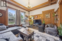Wood-paneled walls and trim throughout, coffered ceiling with a central chandelier, and multiple large windows for natural illumination - 