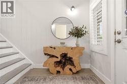 Foyer featuring wood-finish flooring, white baseboards, and a staircase with grey treads - 