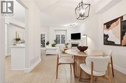 Open-concept living area with light wood-finish flooring, recessed lighting, and a contemporary black geometric chandelier - 