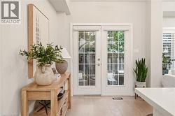 Light wood-finish flooring featuring white double French doors with grid-patterned glass - 