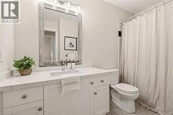 Bathroom featuring a white vanity with an undermount sink, a white countertop, and a mosaic-framed mirror - 