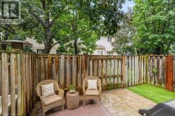 Patio area featuring a wood fence, paver stone hardscaping, and a small section of artificial turf - 
