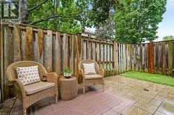 Private outdoor patio featuring large format paver stones, a wooden privacy fence, and a strip of manicured lawn - 