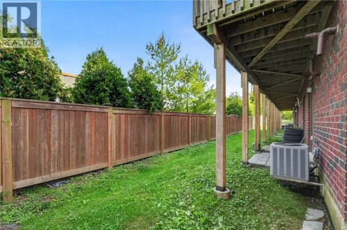 Red brick exterior, wood privacy fence, green lawn, wood deck with support posts - 1169 E Garner Road E Unit# 66, Ancaster, ON 