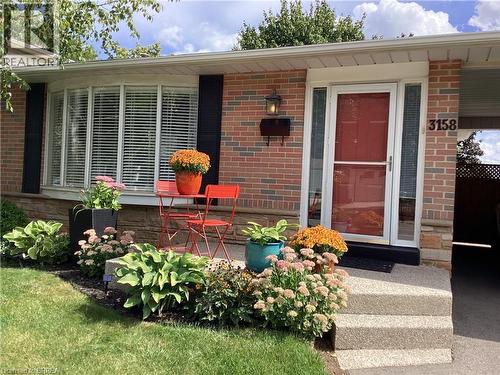 Brick exterior with stone accents, bay window, front entryway with side lights, and concrete steps - 3158 Palmer Drive, Burlington, ON 