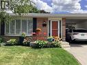 Brick exterior with stone accents, bay window with shutters, covered carport, concrete steps, and a vibrant red front door - 3158 Palmer Drive, Burlington, ON 