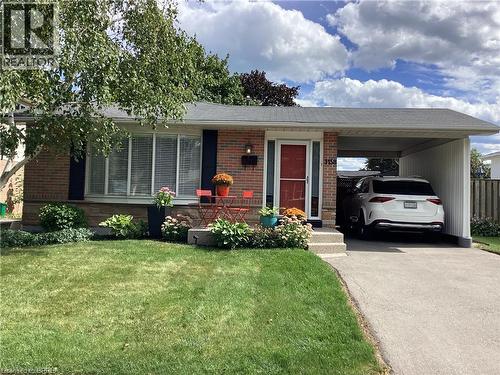 Brick exterior with dark shutters, covered carport, front bay window, and manicured landscaping - 3158 Palmer Drive, Burlington, ON 
