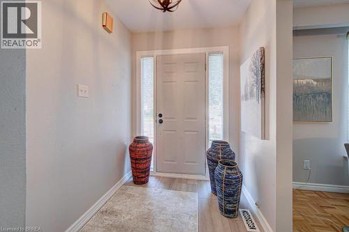 Entryway featuring a paneled door with side lights, wood-finish flooring, and a ceiling-mounted light fixture - 3158 Palmer Drive, Burlington, ON 