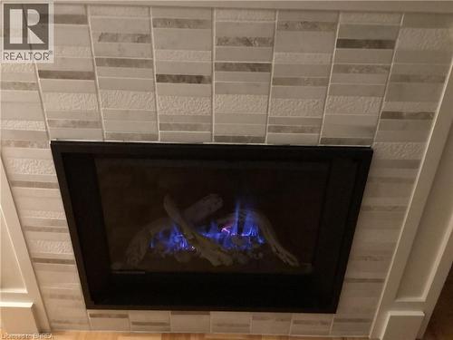 Fireplace with stone tile surround, integrated gas logs, and black trim - 3158 Palmer Drive, Burlington, ON 