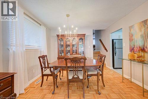 Recessed lighting and a brass chandelier illuminate the dining area with parquet wood flooring - 3158 Palmer Drive, Burlington, ON 