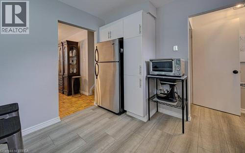 Wood-finish tile flooring, stainless steel refrigerator, and white built-in cabinetry - 3158 Palmer Drive, Burlington, ON 