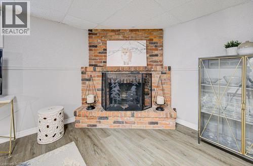 Brick fireplace with a black metal screen and wood-finish flooring - 3158 Palmer Drive, Burlington, ON 