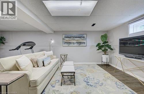 Recessed lighting, wood-finish flooring, a drop ceiling, and a single window provide a bright, functional space - 3158 Palmer Drive, Burlington, ON 