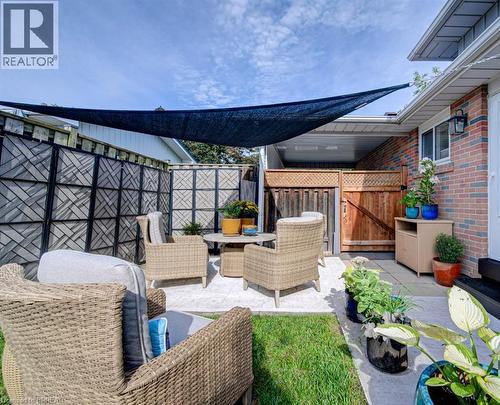 Paved patio area with a sunshade, brick exterior, and wood fencing - 3158 Palmer Drive, Burlington, ON 