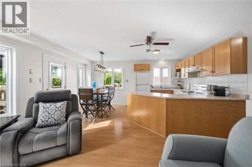 Kitchen and dining area featuring wood-finish flooring, light wood cabinetry, white subway tile backsplash, and a ceiling fan - 67 Apple Tree Drive, Kitchener, ON 